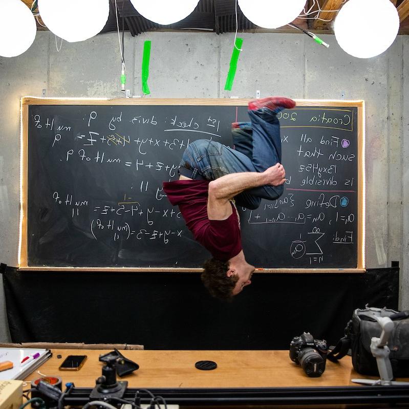 Randolph 数学 professor 迈克尔·佩恩 throws in one of his signature backflips while recording a video for his popular YouTube channel.